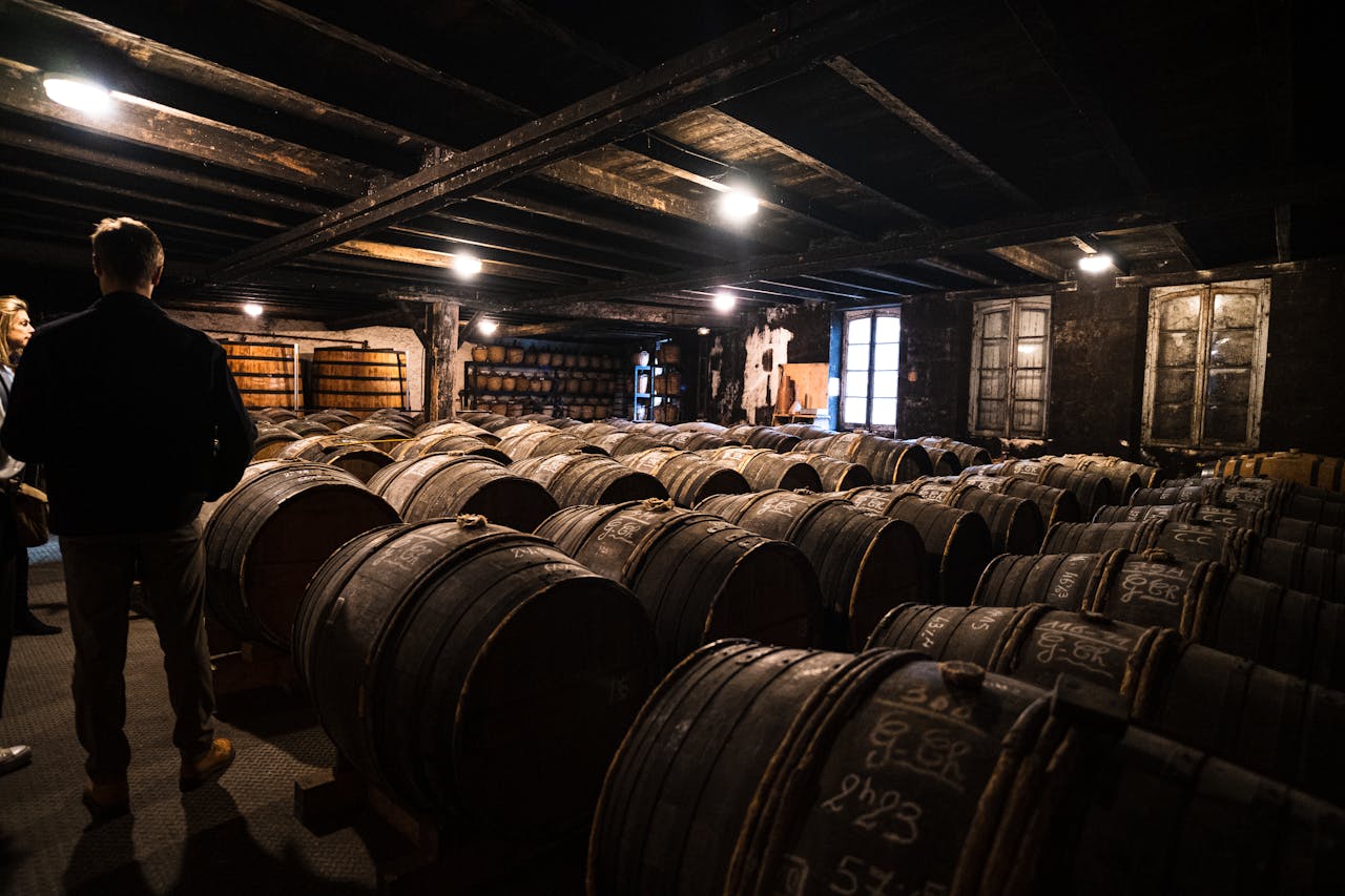A dimly lit wine cellar in Bordeaux with numerous wooden barrels for aging wine.
